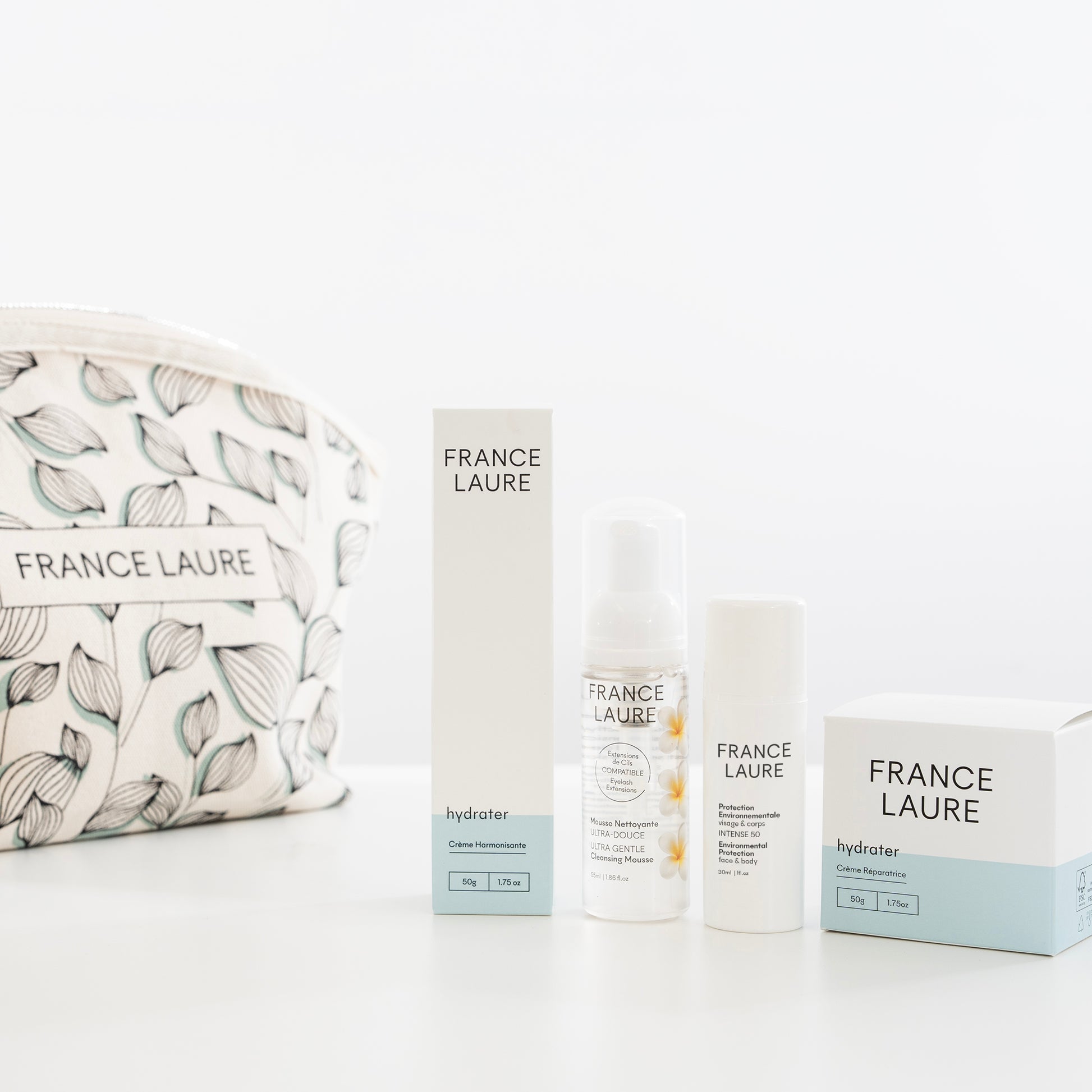 France Laure skincare set with hydrating cream, gentle cleansing mousse, and environmental protection spray, displayed beside a leaf-patterned cosmetic bag.