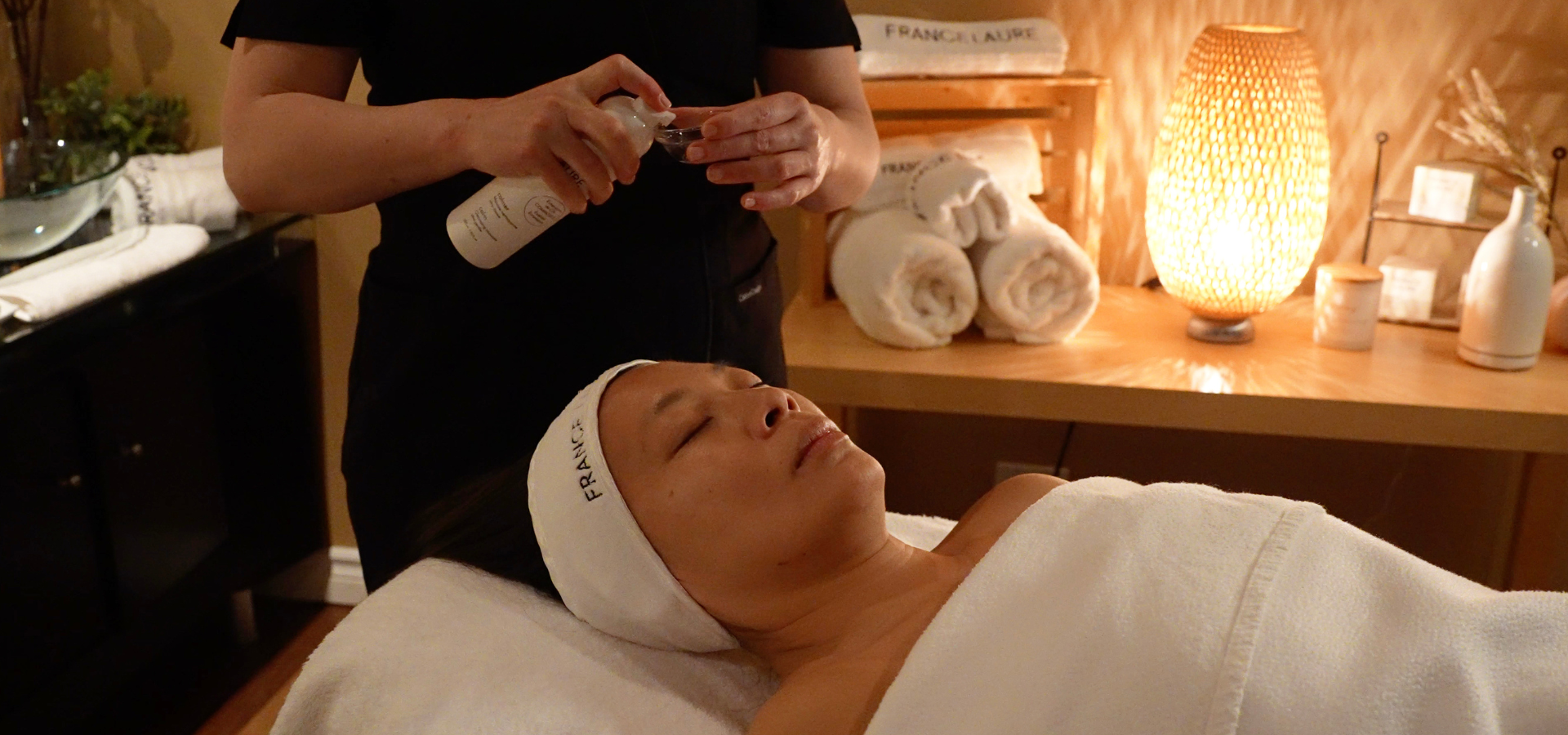 Spa therapist applying skincare product to relaxed client's face during luxury facial treatment session